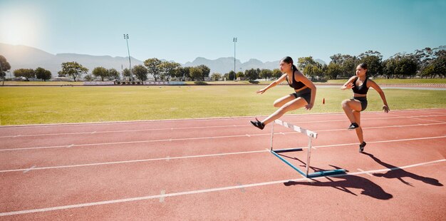 アスリート ランナーと女性のハードル トレーニング コンテスト レースまたはモックアップのサーキットで一緒に女性グループ実行し、チームワークのフィットネスや夏の日差しの屋外トラックでの運動のためにジャンプします。