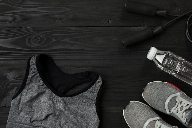 Athlete's set with female clothing and bottle of water on dark background. Top view. Still life. Copy space