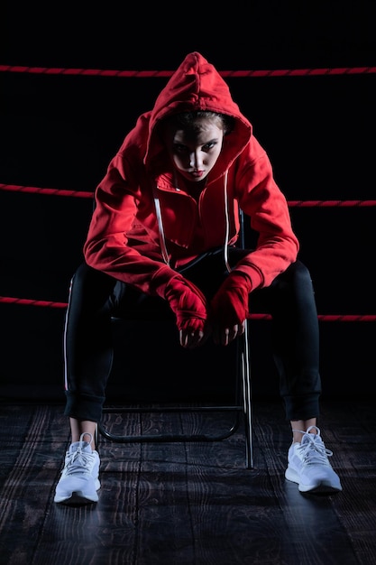 The athlete sits in a chair in the boxing ring after losing the fight Despite the technical preparation the athlete lost the fight in a sweatshirt