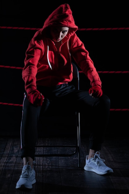 The athlete sits in a chair in the boxing ring after losing the fight Despite the technical preparation the athlete lost the fight in a sweatshirt