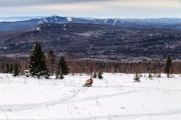 Athlete on a snowmobile moving in the winter forest in the mountains of the Southern Urals.