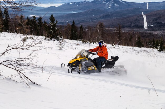 Atleta su una motoslitta che si muove nella foresta invernale