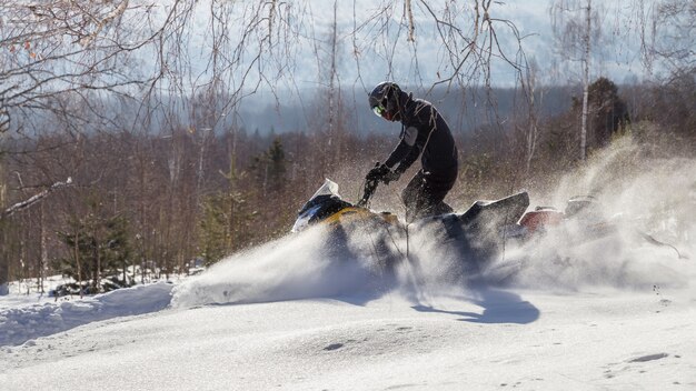 Athlete on a snowmobile in the winter forest.