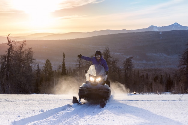 Athlete on a snowmobile in the winter forest.