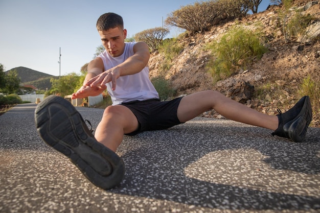 An athlete stretches after a workout by touching his feet with his hands