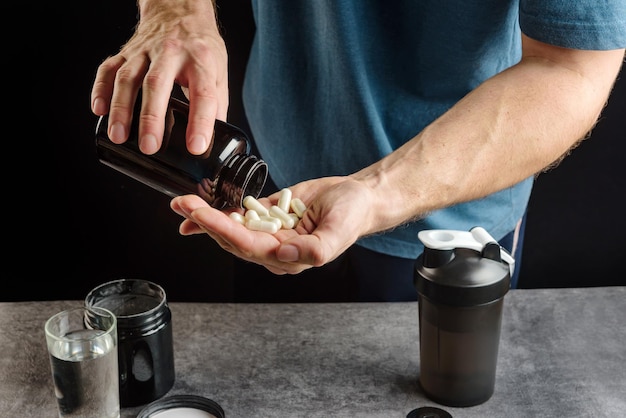 Athlete takes supplements. Capsules with amino acid on the palm close-up.