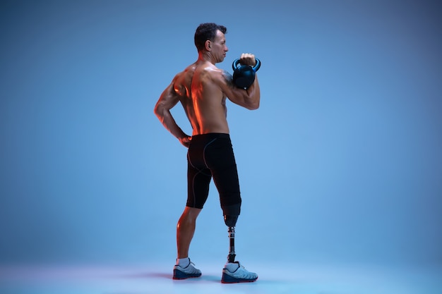 Спортсмен-инвалид или человек с ампутированной конечностью, изолированные на синей стене