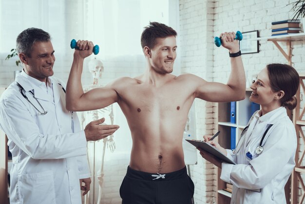 Athlete with dumbbells in clinic room.