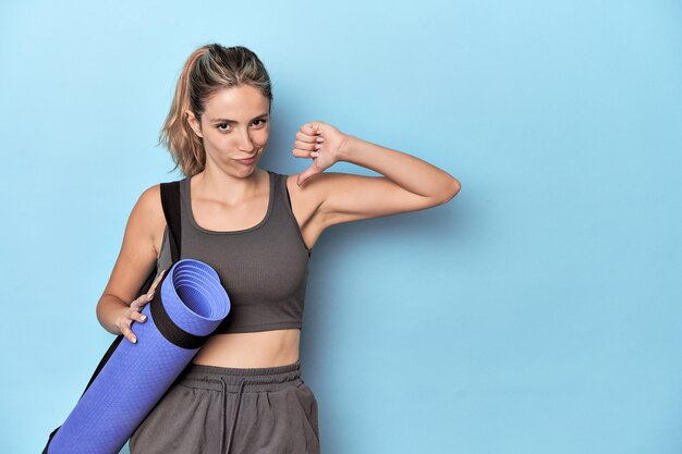 L'atleta con un tappetino nello studio blu si sente orgoglioso e sicuro di sé come esempio da seguire