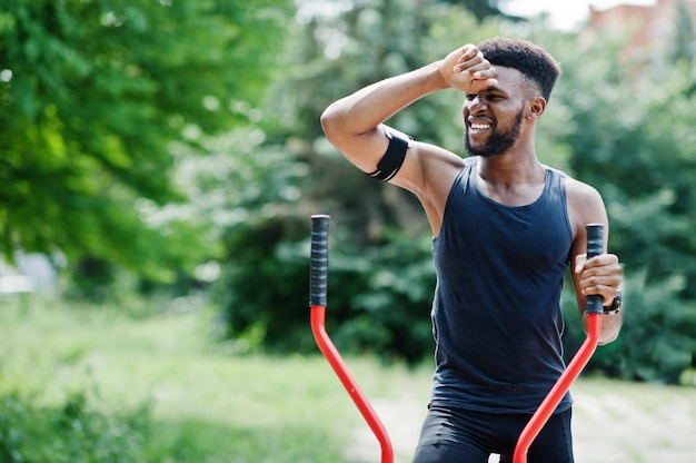 Athlete with running sports arm case for mobile phone, doing exercises on the street workout simulators