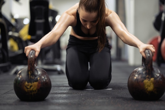 Foto atleta donna che fa push up su due kettlebell