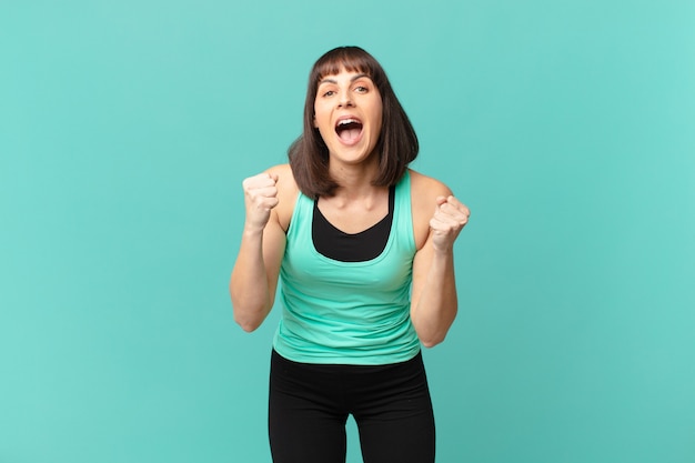 Athlete woman feeling shocked, excited and happy, laughing and celebrating success, saying wow!