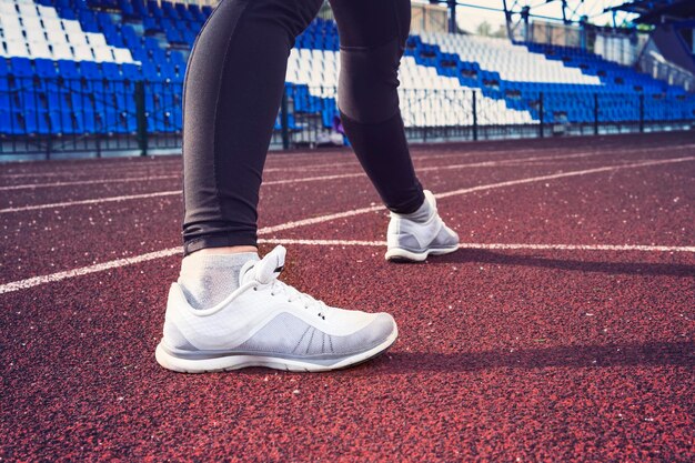 Athlete woman in running start pose on the city street sport\
tight clothes sports shoes in the foreground rear view