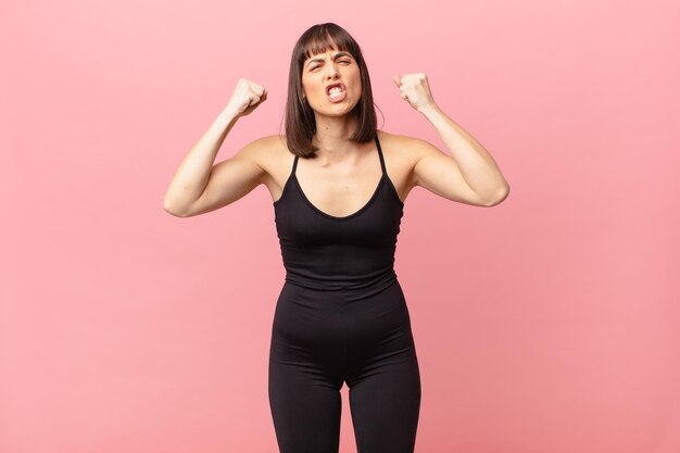 Athlete woman shouting aggressively with an angry expression or with fists clenched celebrating success