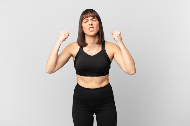 athlete woman shouting aggressively with an angry expression or with fists clenched celebrating success