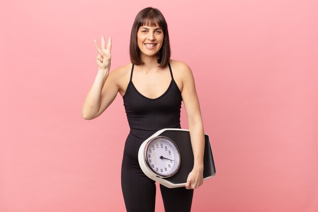 Athlete woman smiling and looking friendly, showing number three or third with hand forward, counting down