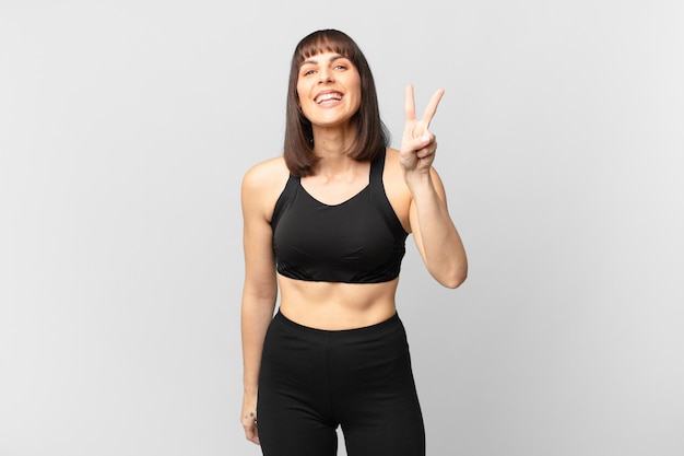 Athlete woman smiling and looking friendly, showing number two or second with hand forward, counting down