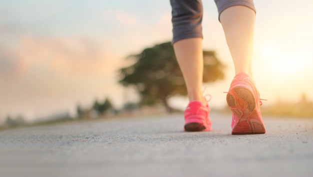 Athlete woman walking exercise on rural road in sunset background