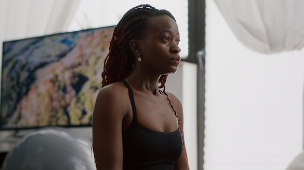 Athlete woman with dark skin wearing sportswear practicing yoga at home