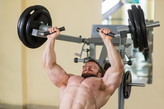 Athlete working out in gym Bodybuilder doing exercises in gym Strong man concentrated on sport