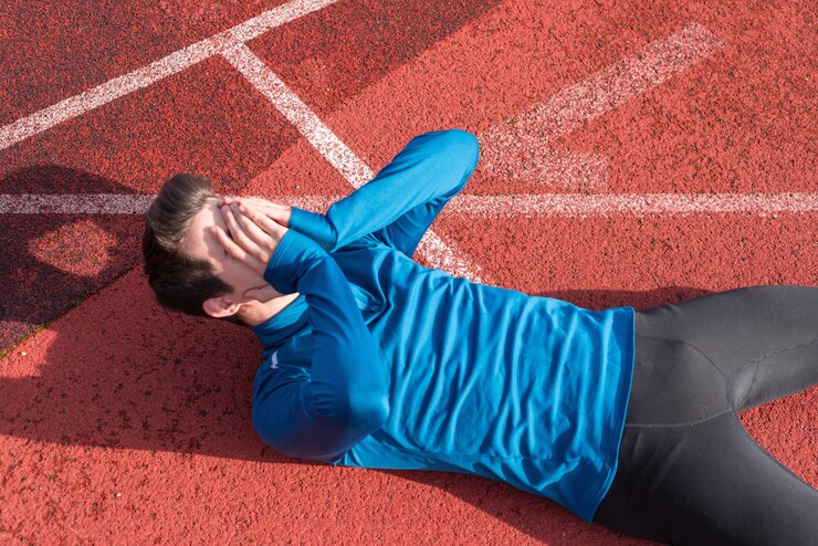 Athlete young man tired, lying on running track.