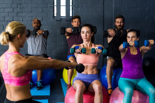 Athletes exercising with trainer in gym