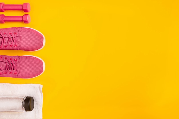 Photo athletes set with female clothing dumbbells and bottle of water on yellow background