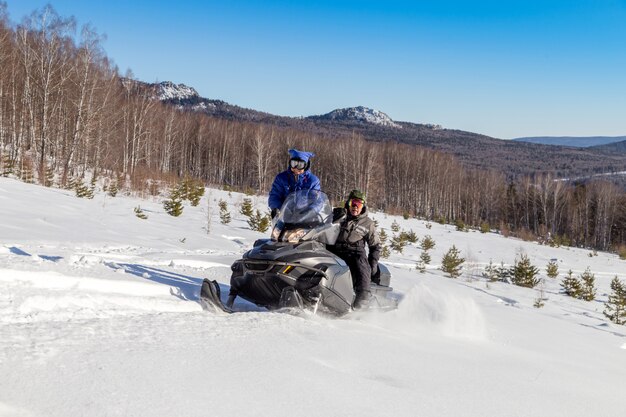 Atleti su una motoslitta nella foresta invernale.