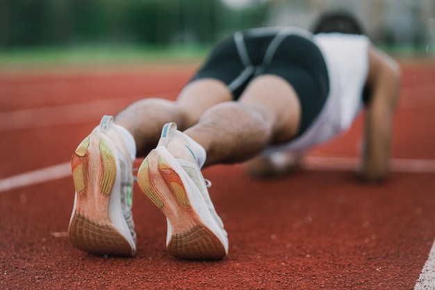 Atleti sportivi uomo corridore che indossa abiti sportivi bianchi per fasciare stretching e riscaldamento prima di esercitarsi su una pista da corsa in uno stadio runner sport concept