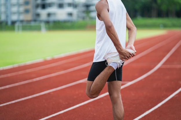 Athletes sport man runner wearing white sportswear to stretching and warm up before practicing on a running track at a stadium Runner sport concept