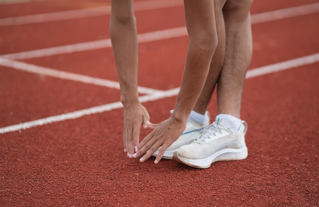 Спортсмены-бегуны в белой спортивной одежде разминаются и разминаются перед тренировкой на беговой дорожке на стадионе.