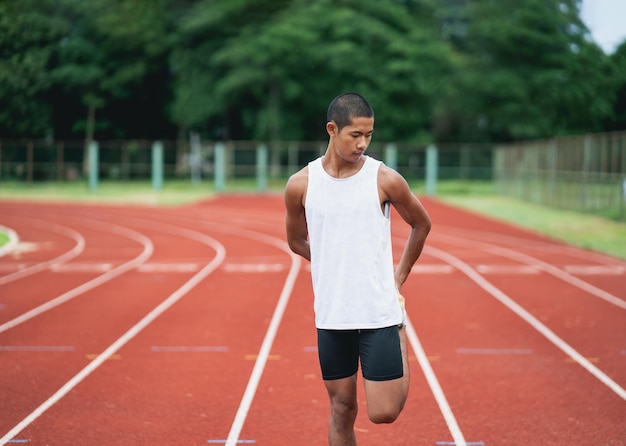 Athletes sport man runner wearing white sportswear to stretching and warm up before practicing on a running track at a stadium Runner sport concept