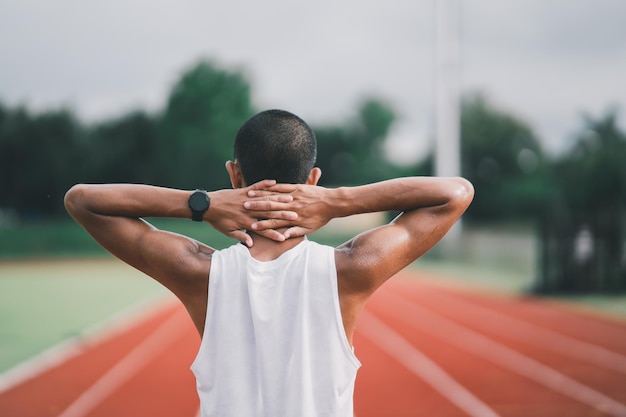 Athletes sport man runner wearing white sportswear tired wipe sweat and resting after practicing on a running track at a stadium Runner sport concept