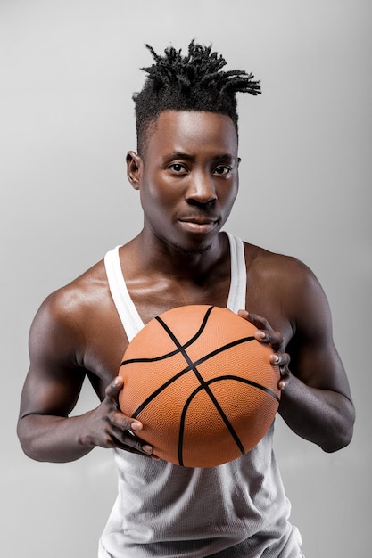 Athletic african-american basketball player holding basketball\
ball