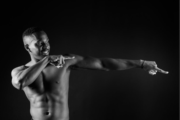 Athletic african american man topless big muscles dark background studio