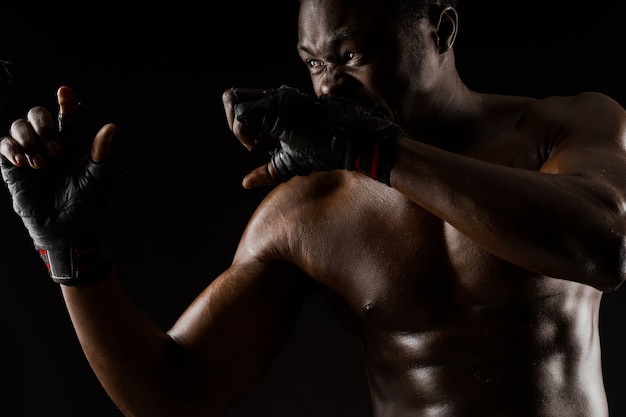 Athletic african fighter on black surface