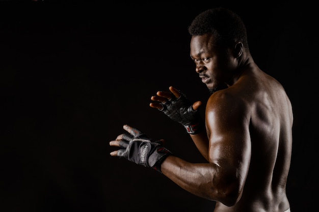 Athletic african fighter on black surface