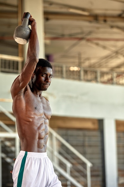 Athletic black young man lifting a heavyweight barbell in outdoor gym under the bridge Healthy lifestyle concept