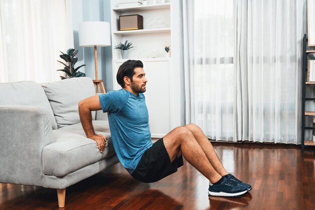 Athletic body and active sporty man using furniture for gaiety home exercise