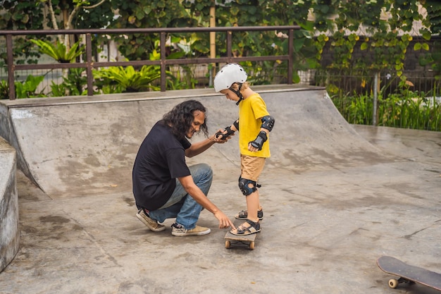 Athletic boy learns to skateboard with a trainer in a skate park Children education sports