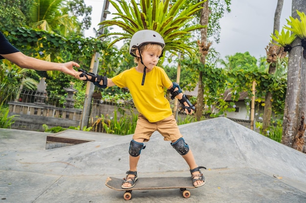 Athletic boy learns to skateboard with a trainer in a skate park children education sports