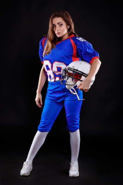 Athletic brunette posing as american football girl on black\
background