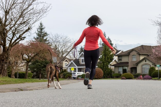 ボクサー犬と一緒に外で走っている運動白人成人女性