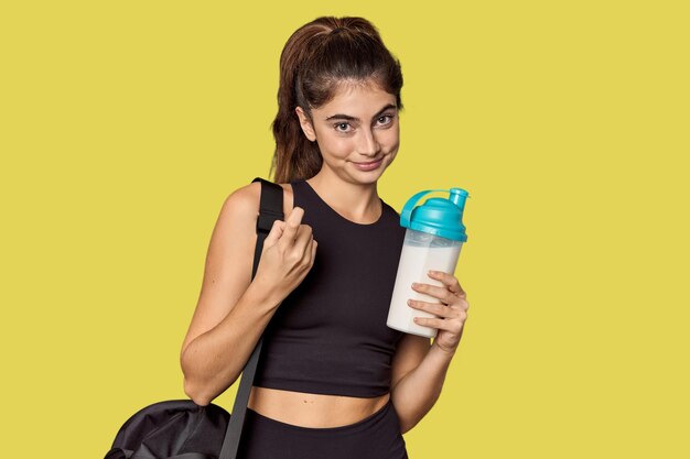 Athletic Caucasian woman holding protein shake pointing with finger at you