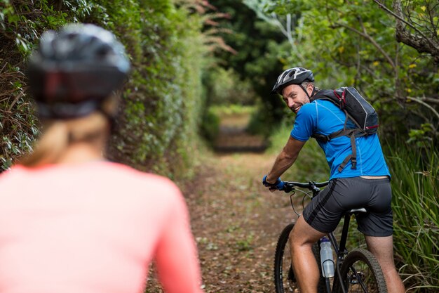 Athletic couple cycling in forest