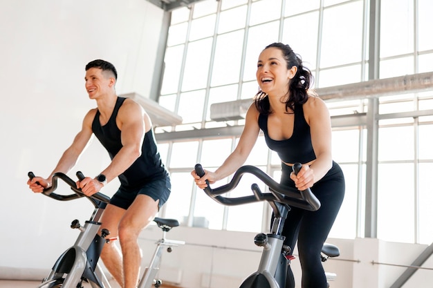 Athletic couple of cyclists train on static bicycle simulator man trainer and fitness woman