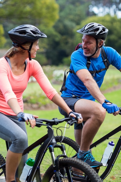 Athletic couple looking face to face while riding bicycle