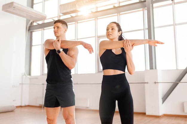 Athletic couple in sportswear warm up in the gym in the morning fitness girl and coach man