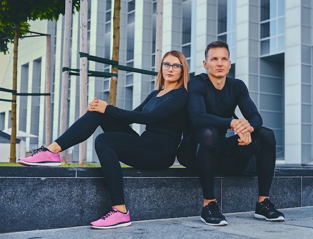 The athletic fitness couple modern building background.