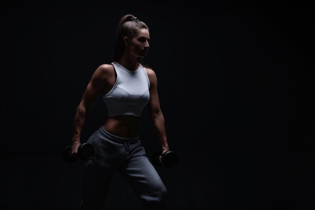 Athletic fitness woman posing in the studio on a dark\
background photo of an attractive woman in fashionable sportswear\
sports and healthy lifestyle